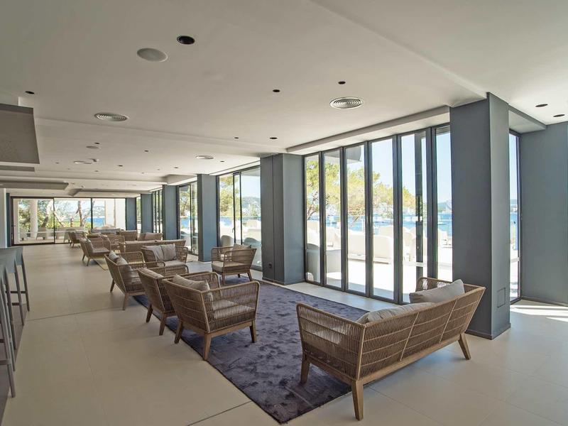 Lichte, moderne lounge met zitgroepen en grote ramen met uitzicht naar buiten.