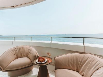 Balkon se dvěma pohodlnými křesly, stolkem a výhledem na moře za jasné oblohy.