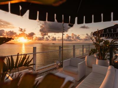 Sitzecke auf einer Terrasse mit Blick auf Sonnenuntergang über dem Meer.