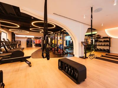 Moderner Fitnessraum mit Laufbändern, Hanteln und Trainingsgeräten in hellem, geräumigem Raum.