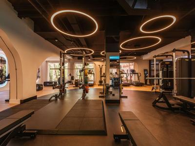 Moderner Fitnessraum mit Fitnessgeräten und warmen Deckenleuchten.