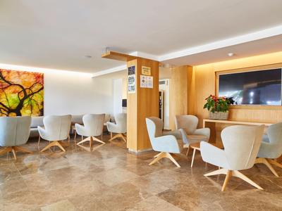 Moderní hotelová lounge s pohodlnými křesly a uměleckým dílem na zdi.