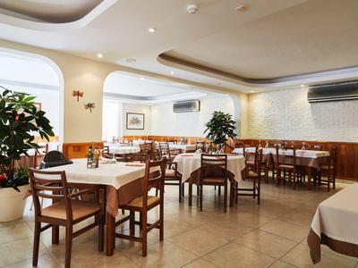 Salle à manger lumineuse et accueillante avec tables dressées, meubles en bois et plantes.
