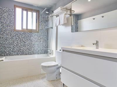 Salle de bains moderne avec baignoire, toilettes et grand miroir avec meuble lavabo.