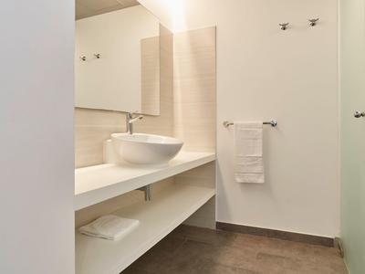Salle de bain moderne avec lavabo sur long plan de travail blanc et grands miroirs.