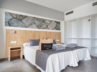 Chambre d'hôtel moderne avec lit double, meubles en bois et décoration murale en pierre.