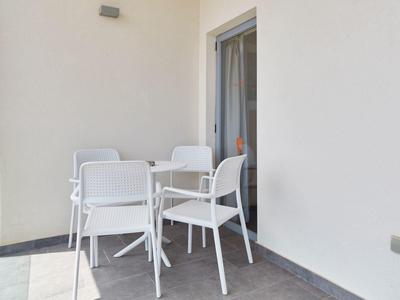 Balcon avec table blanche moderne et quatre chaises devant une porte vitrée