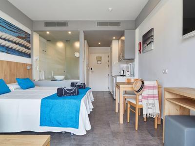 Chambre d'hôtel moderne avec deux lits simples, accents bleus et bureau avec chaises.