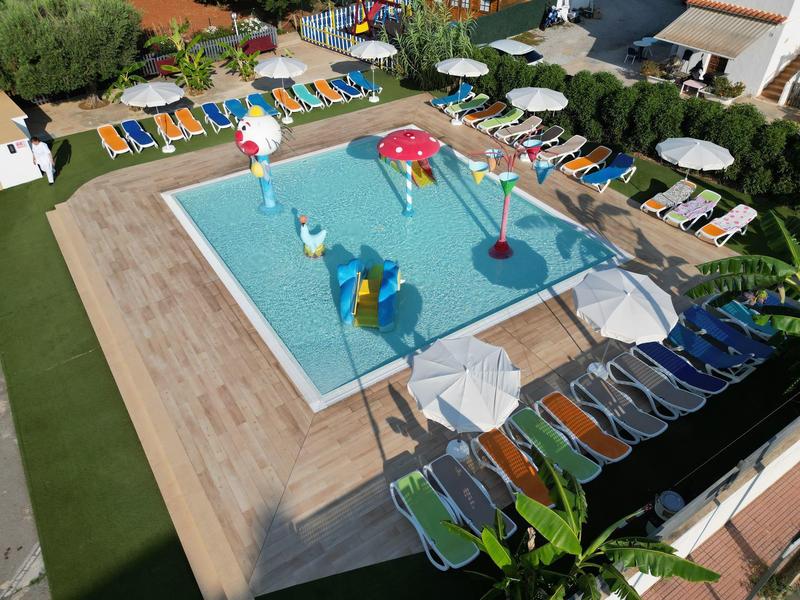 Vue sur une petite piscine avec des jouets aquatiques colorés et des chaises longues extérieures.