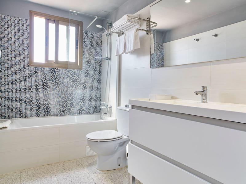 Salle de bains moderne avec baignoire, toilettes et grand miroir avec meuble lavabo.