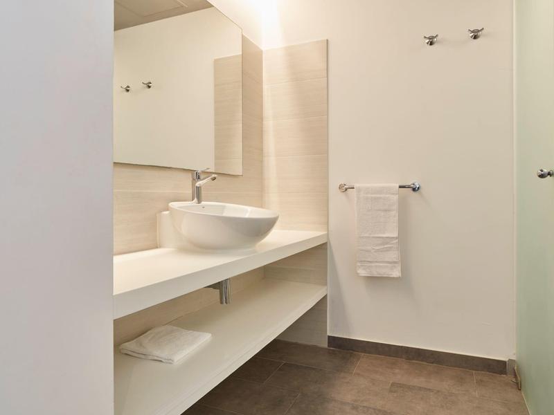 Salle de bain moderne avec lavabo sur long plan de travail blanc et grands miroirs.