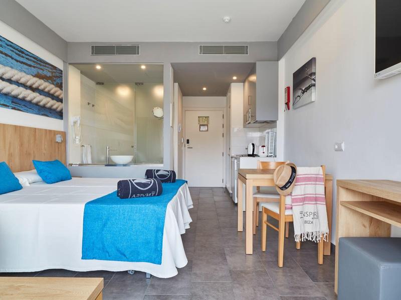 Chambre d'hôtel moderne avec deux lits simples, accents bleus et bureau avec chaises.