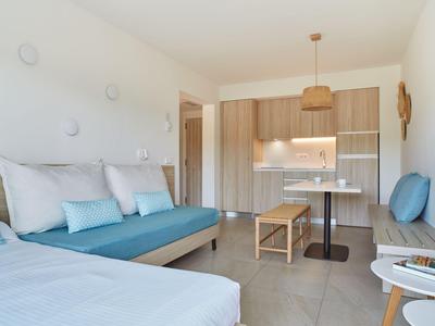 Světle moderní apartmán s kuchyňským koutem, posezením a pohovkou s modrými polštáři.