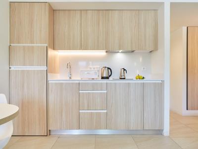 Moderní, světlý kuchyňský kout s dřevěnými předními panely a minimalistickým designem v bytě.