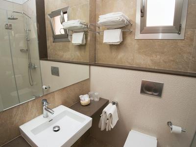 Moderní hotelová koupelna se dřezem, ručníky a sprchovým koutem.