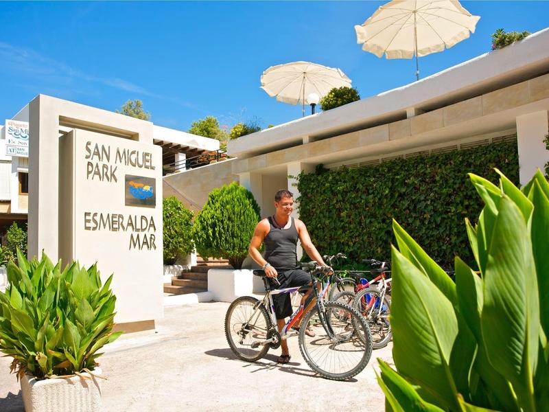 Muž jede na kole před vchodem do resortu San Miguel Park Esmeralda Mar.