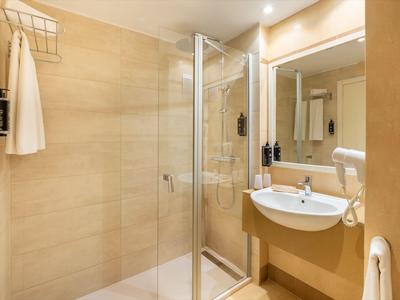 Baño moderno con cabina de ducha, lavabo y secador en tonos cálidos beige y marrón.