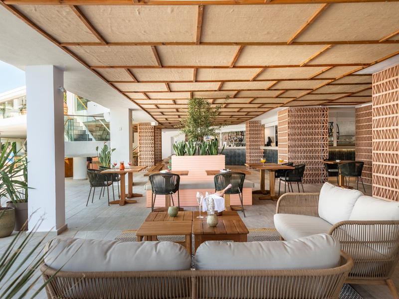 Offener Hotel-Loungebereich mit Sitzmöbeln, Tischen und Pflanzen in modernem Design.