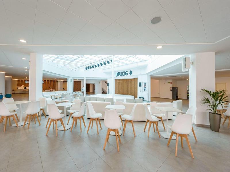 Helles, modernes Innenbereich-Café mit weißen Tischen und Stühlen im Hotel.