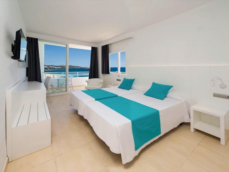 Helles Hotelzimmer mit Doppelbett, Meerblick und Balkon, modern eingerichtet.