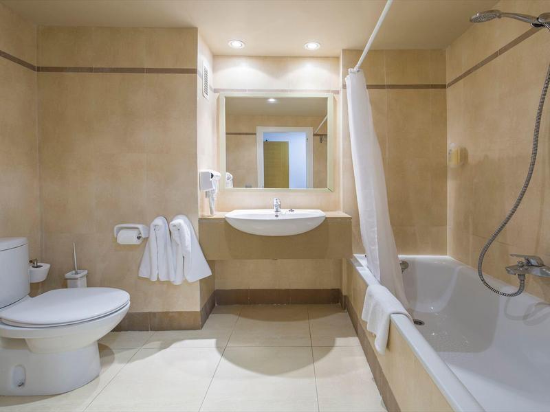 Modernes Badezimmer mit Badewanne, Waschbecken, Toilette und hellen Fliesen.