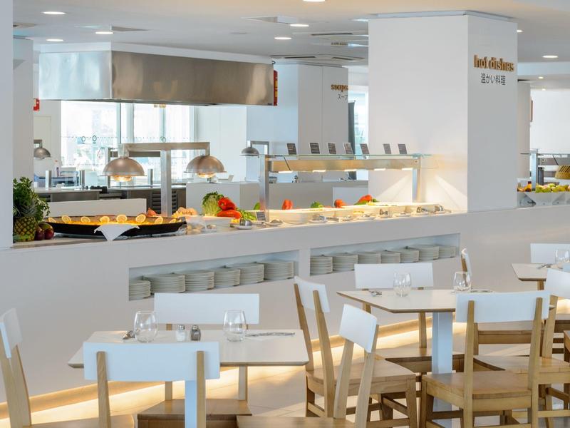 Helles, modernes Hotelrestaurant mit Holztischen und Stühlen sowie Buffetbereich im Hintergrund.