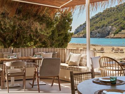 Gemütliche Außenterrasse mit Holzmöbeln und Blick auf den Strand und das Meer