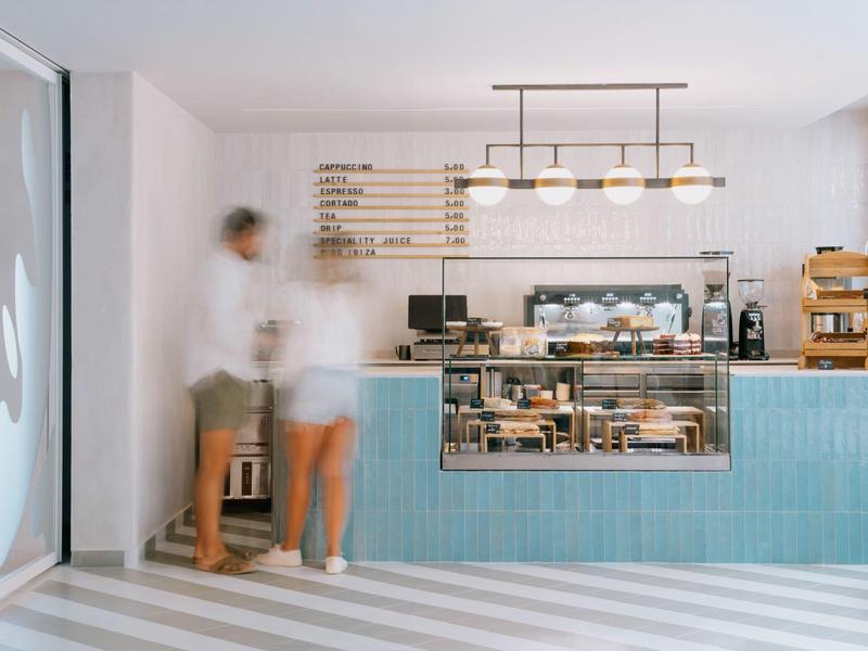 Réception d'hôtel moderne avec carrelage bleu, éclairage et deux personnes en conversation.