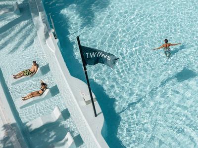 Area piscina con due persone che prendono il sole accanto all'acqua e un nuotatore nell'acqua limpida