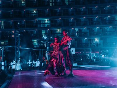 Due musicisti si esibiscono dal vivo sul palco in una grande sala concerto buia con balconi.