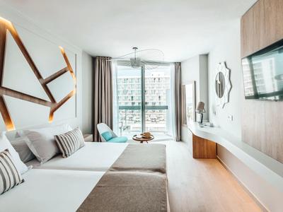 Modern eingerichtetes Hotelzimmer mit zwei Betten und großem Fenster mit Blick nach außen.