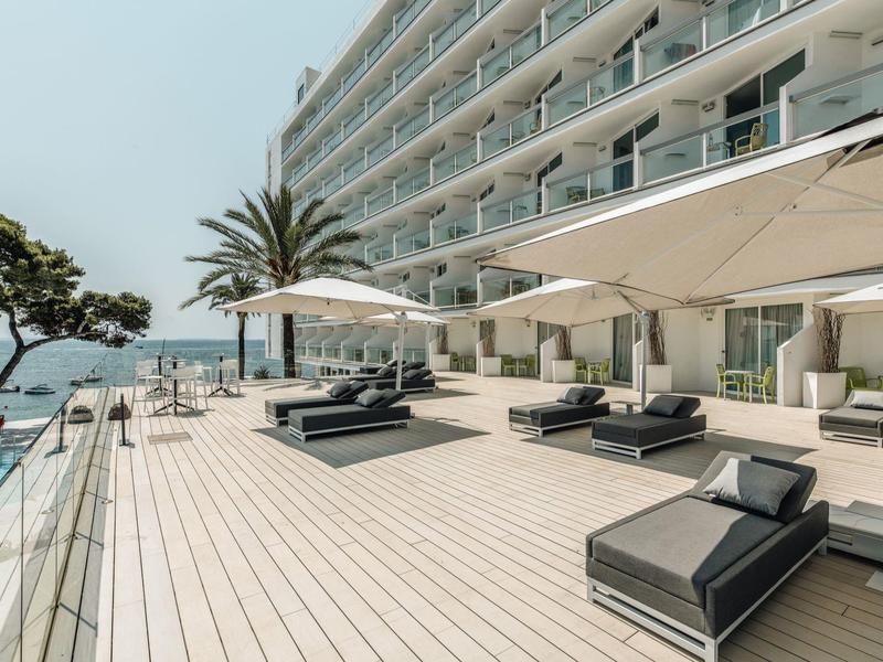 Moderní hotelová terasa s posezením, slunečníky a výhledem na moře.