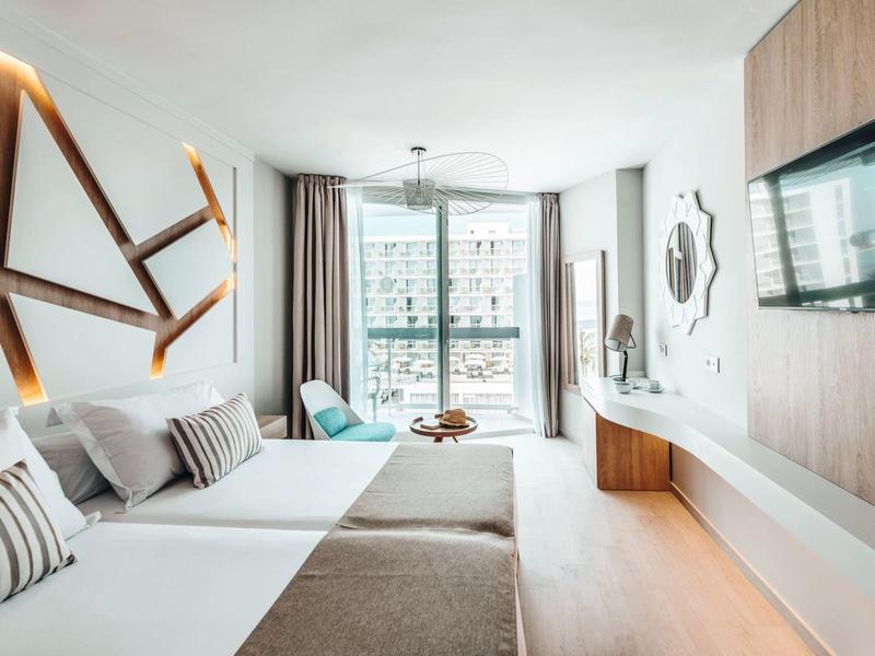 Moderně zařízený hotelový pokoj se dvěma postelemi a velkým oknem s výhledem ven.