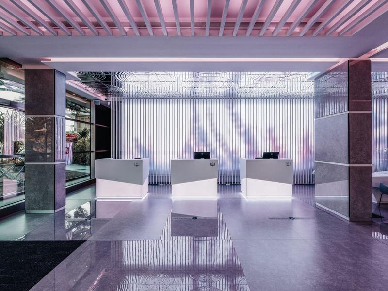 Moderní hotelová recepce s elegantními bílými přepážkami a skleněnými prvky.