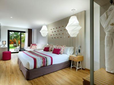Modern hotel room with a double bed, wooden floor, and large window overlooking greenery.