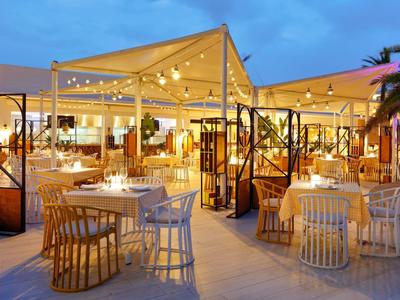 Outdoor restaurant with string lights and modern furniture during evening at a resort.
