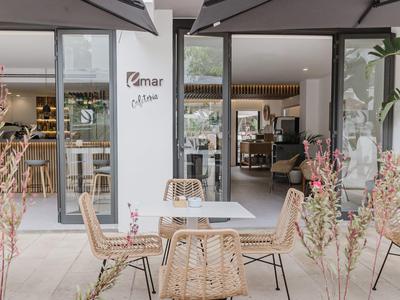 Moderne buitenruimte van een restaurant met ronde stoelen en tafels voor grote glazen ramen.