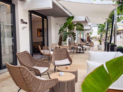 Terras met comfortabele stoelen, tafels en planten voor hotelkamers onder zonneschermen.