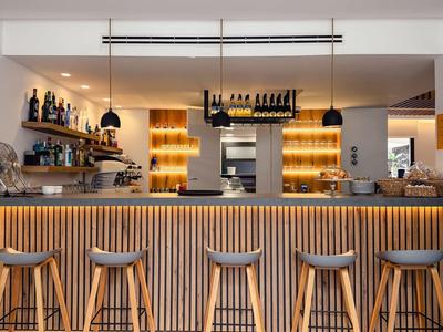 Moderne hotelbar met houten bar en vijf krukken in warm licht.