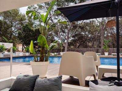 Moderne buitenzitgroep met kussens en parasol bij het zwembad in een tuinomgeving.