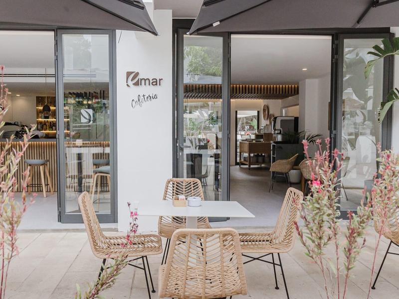 Moderne buitenruimte van een restaurant met ronde stoelen en tafels voor grote glazen ramen.