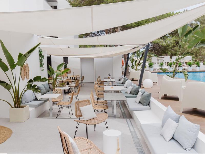 Moderne buitenruimte met zitplaatsen en zwembad onder witte zonneschermen.