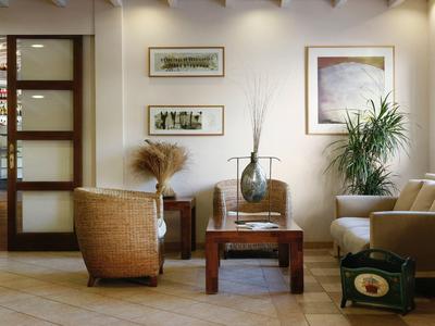 Pohodlný hotelový lounge s křesly, dřevěným stolem a zelenými rostlinami.