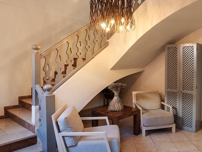 Pohodlný koutek s dvěma křesly, stínidlem a dekorativní přepážkou pod schodištěm.