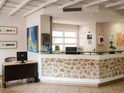 Recepční prostor s kamenným pultem, dřevěným stropem a stolem s počítači.