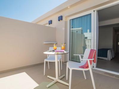 Balkon s stolem, dvěma židlemi a nápoji vedle skleněných dveří hotelového pokoje.