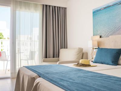 Gemütliches Hotelzimmer mit Bett, Sofa, Balkon und Meerblick-Wandbild.