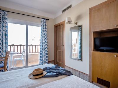 Hotelový pokoj s postelí, dřevěnou skříní, balkonem a výhledem ven.