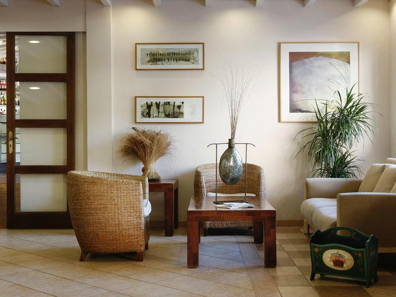 Pohodlný hotelový lounge s křesly, dřevěným stolem a zelenými rostlinami.