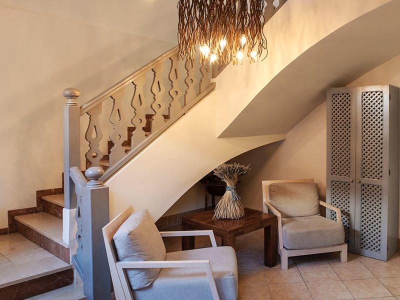 Pohodlný koutek s dvěma křesly, stínidlem a dekorativní přepážkou pod schodištěm.